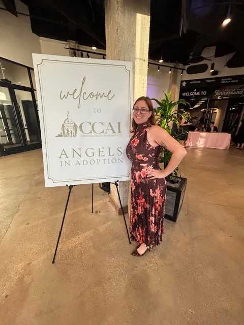Diana beside the CCAI Angels in Adoption welcome sign